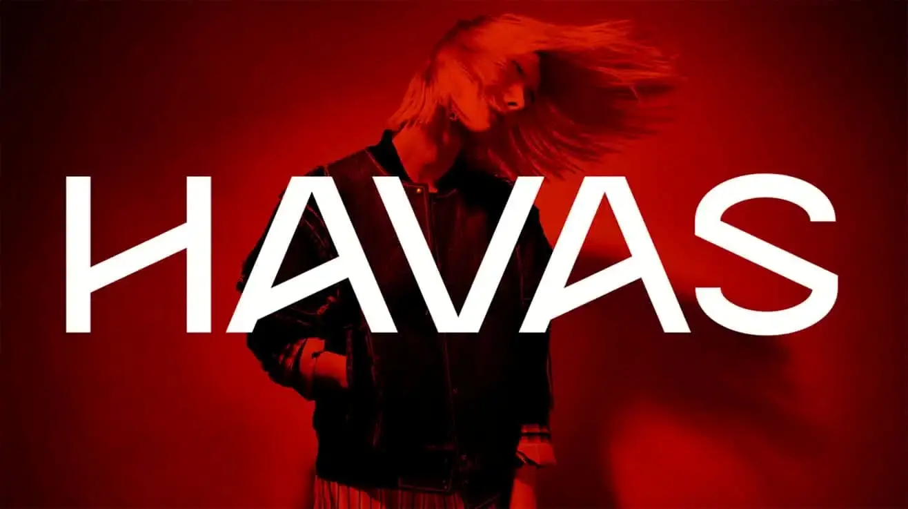 Merkcampagnebeeld van Havas Media Network: het HAVAS-woordmerk over een bewegende figuur in diep rood licht