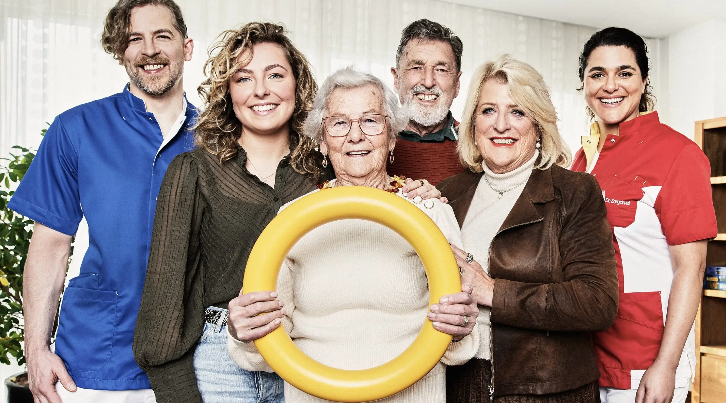 Bewoners, familieleden en zorgmedewerkers van De Zorgcirkel samen, de bewoonster in het midden met een gele ring