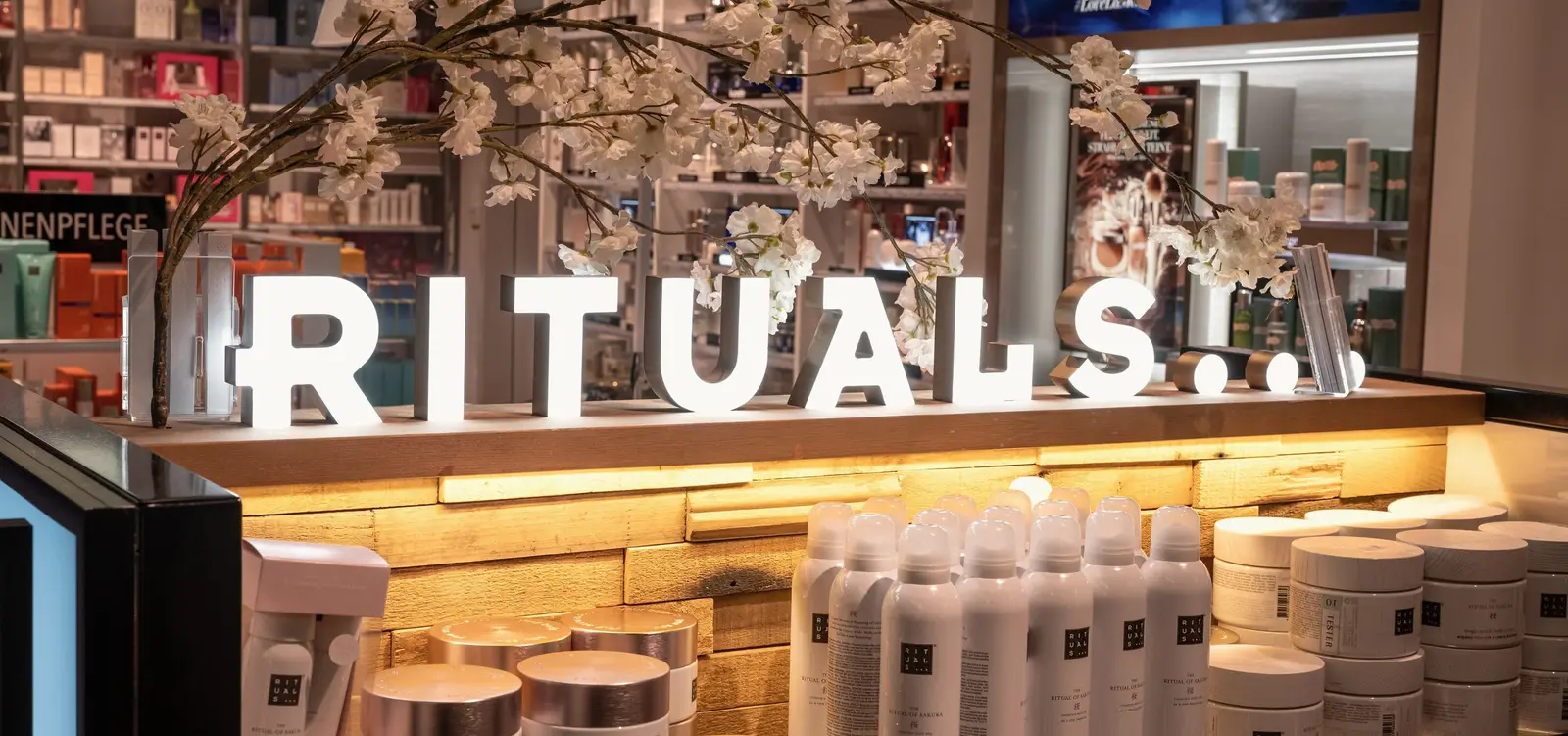 Rituals-winkel, verlicht RITUALS-logo met een kersenbloesemtak boven de toonbank